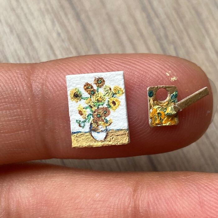 Miniature paper figures: A tiny Van Gogh Sunflowers painting and easel on a fingertip, showcasing immense detail.