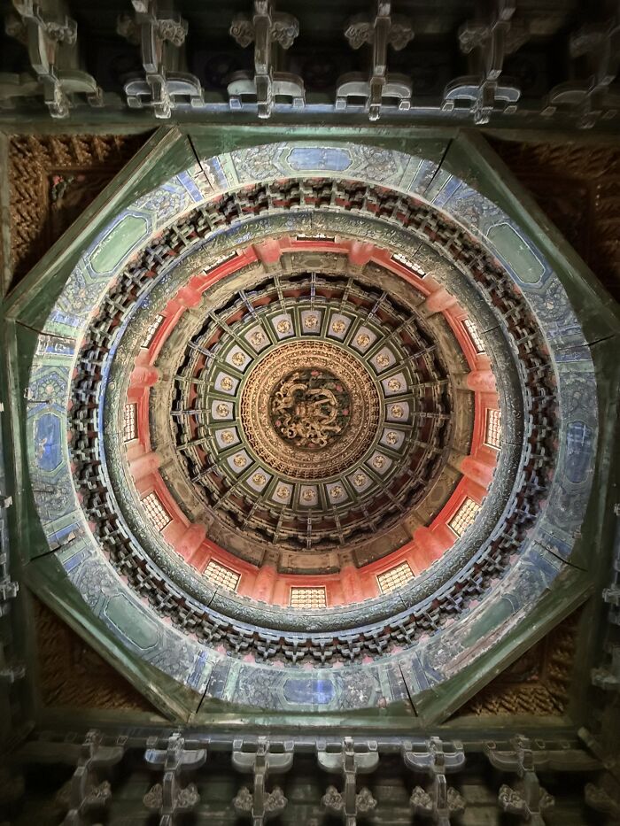 Intricate, colorful ceiling of a historical building in China, showcasing detailed artwork and traditional architecture.