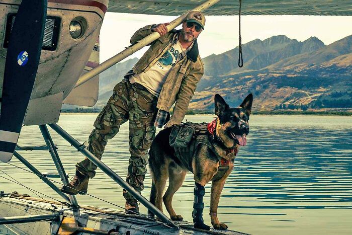 Brad Pitt standing with German shepherd by plane in survival movie Brad Pitt standing with German shepherd by plane in survival movie