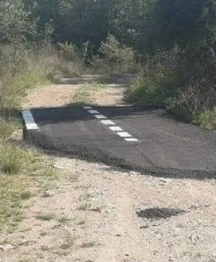 A short paved road segment ending abruptly at a dirt path, illustrating an unusual application of Slavic Science.