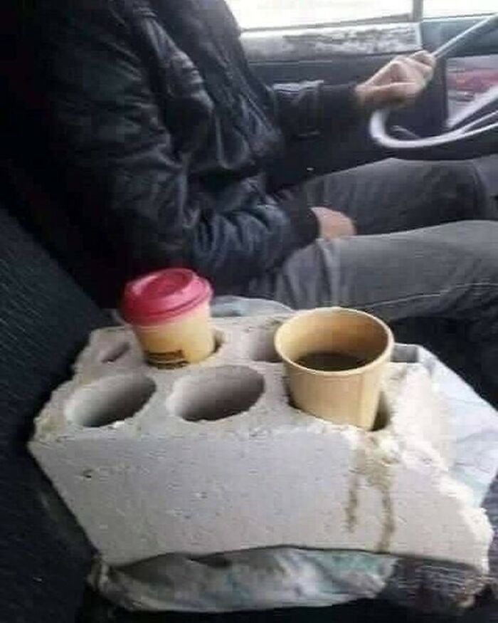 A cinder block serving as a cup holder for two drinks in a car, demonstrating practical Slavic Science.