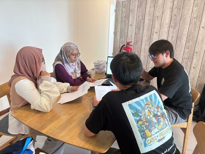 Volunteers discussing strategies to help street cats, showcasing the technology and local action involved in their mission.
