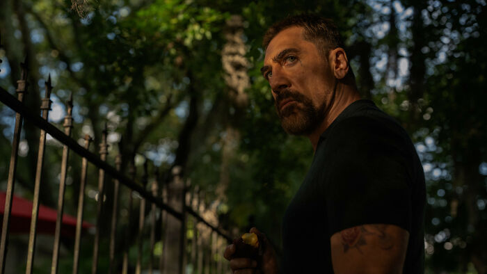 Cape Fear character standing by iron fence in dark forest