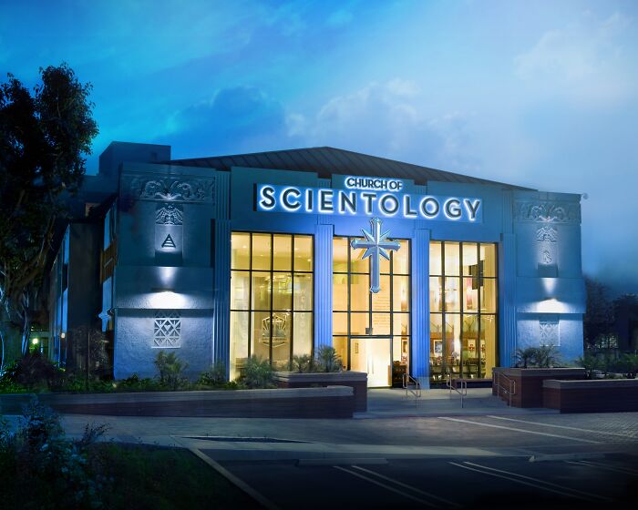 The Church of Scientology building, an architectural mystery, stands illuminated at dusk, one of many unsolved mysteries.
