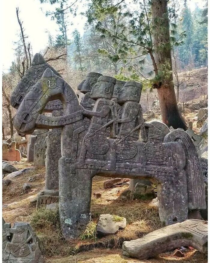 Old historical stone sculpture of horse with three riders in forest setting