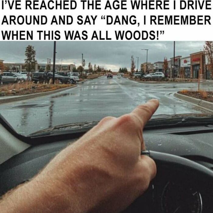Driver pointing at developed shopping area reminiscing about when it was woods