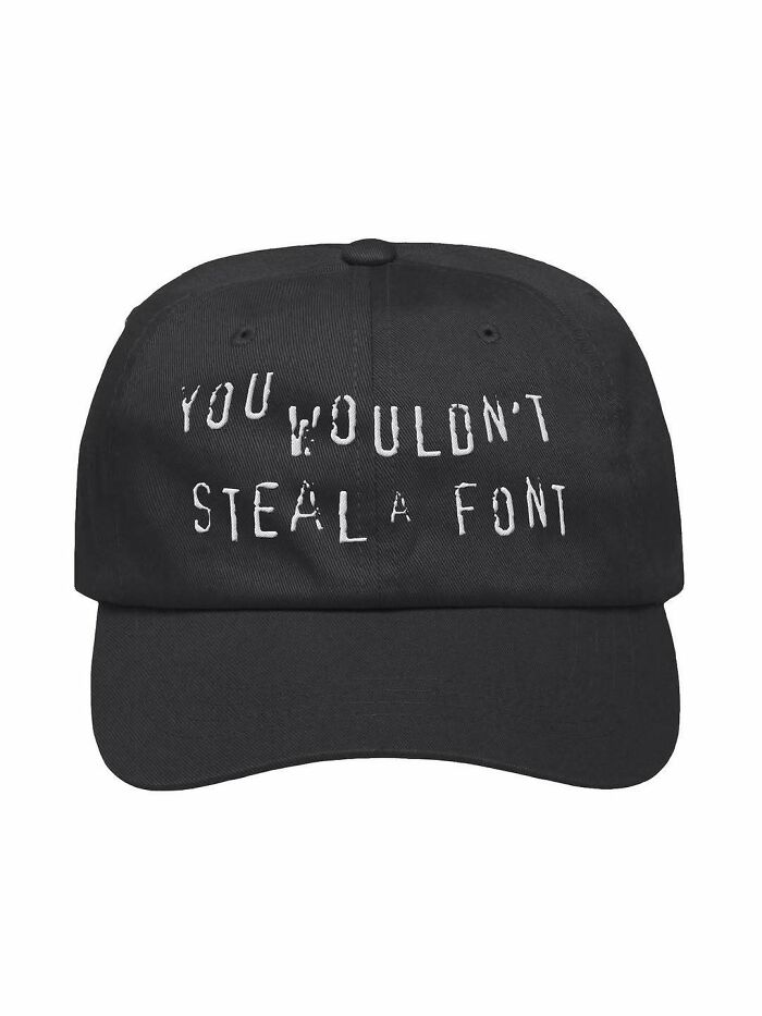 Black baseball cap with white text that reads You wouldn't steal a font, showcasing design humor.