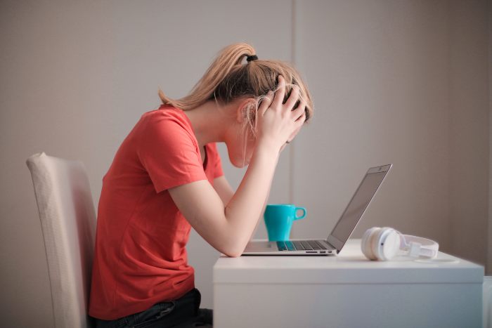 A young woman looking distressed while using a laptop, representing the worry caused by dopamine sites. A young woman looking distressed while using a laptop, representing the worry caused by dopamine sites.