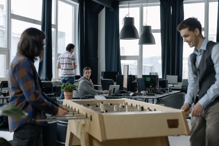 Gen Z employees at an office with a foosball table, showing a potential distraction from viral dopamine sites. Gen Z employees at an office with a foosball table, showing a potential distraction from viral dopamine sites.