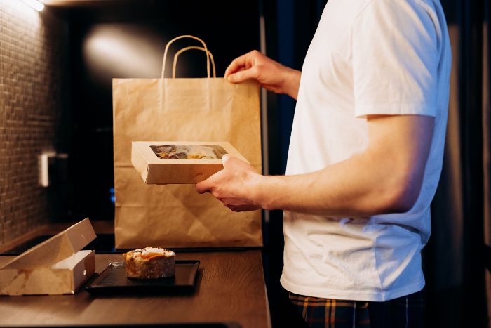 A person holding a takeout box, representing instant gratification from viral dopamine sites and the new trend. A person holding a takeout box, representing instant gratification from viral dopamine sites and the new trend.