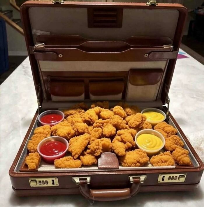 Cursed image of chicken nuggets with sauces served inside an open briefcase