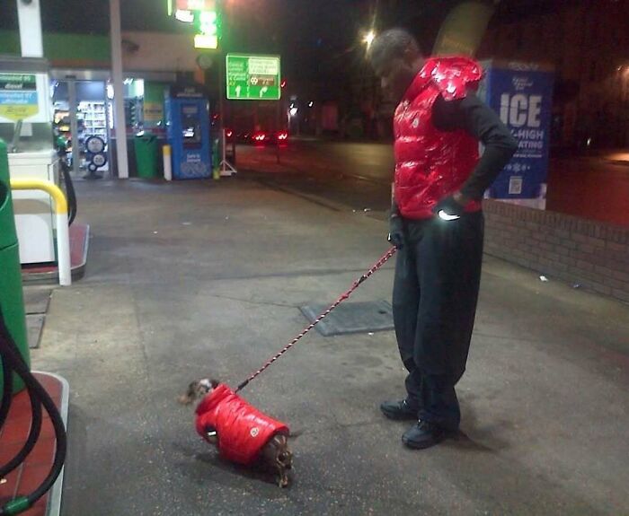 Man and dog wearing matching red jackets at gas station in cursed image