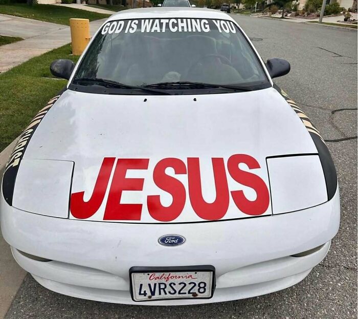White Ford car with large red Jesus text and God is watching you windshield decal