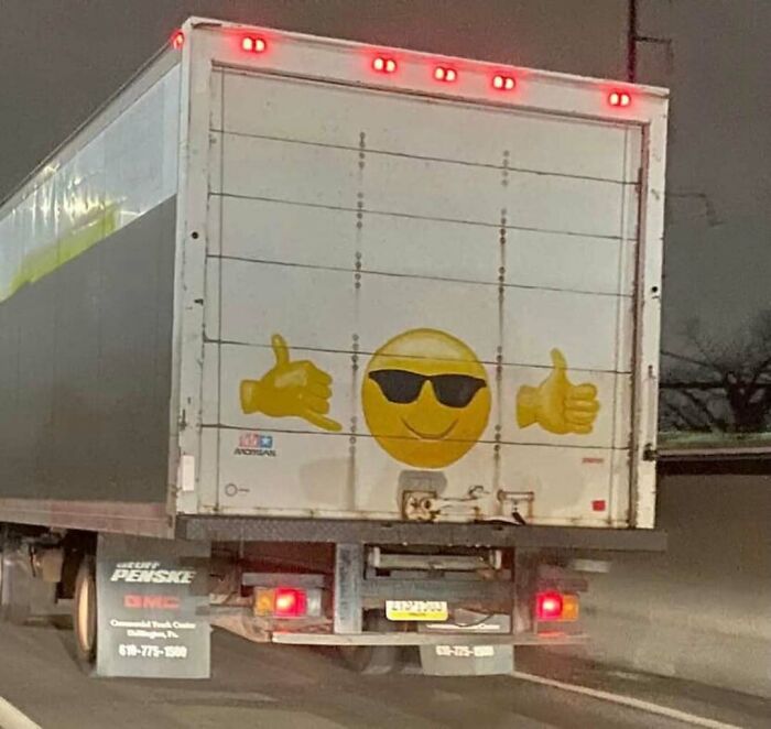 Rear of truck featuring a large smiling emoji with sunglasses decal