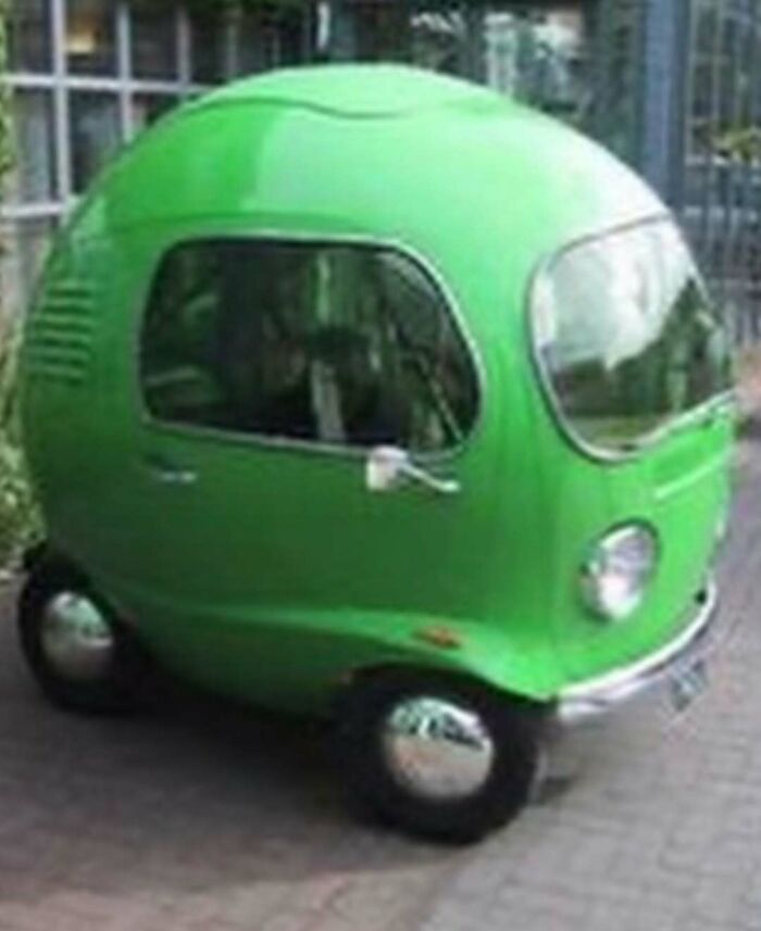 Tiny green egg-shaped microcar with rounded windows and headlights