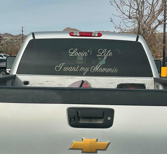 Silver Chevrolet truck with rear window decal saying Lovin life I want my mommie