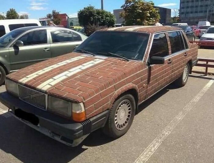 Car painted to look like brick wall in parking lot