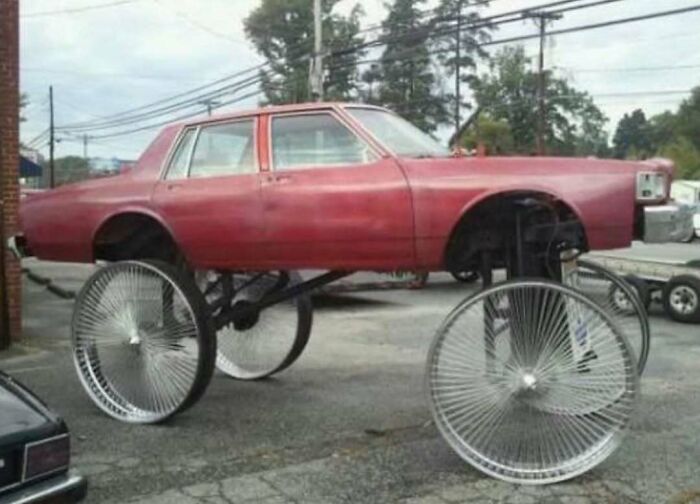 Red car elevated on large custom wire spoke wheels