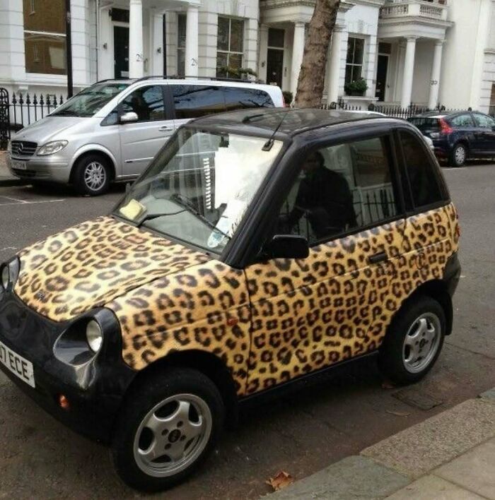 Cursed image of a small car with leopard print on its body parked on a street