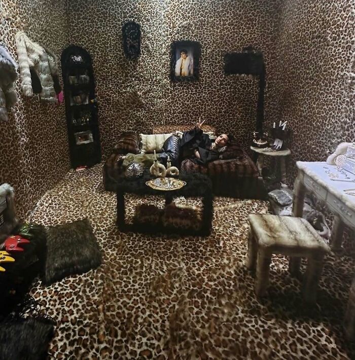 Room fully covered in leopard print fabric with person lounging on couch