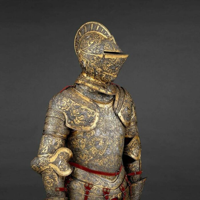 Ornate gold and black decorated medieval knight armor displayed on a mannequin