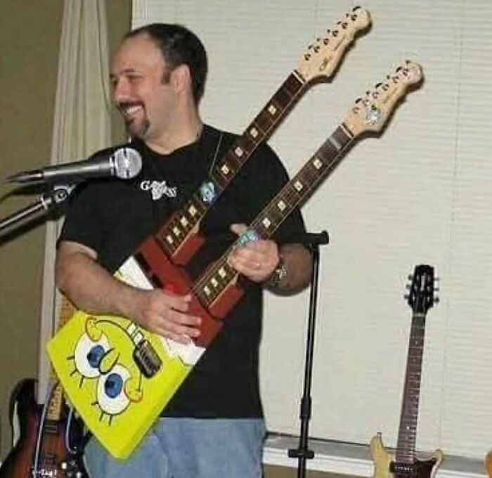 Man holding a double-neck guitar with a SpongeBob SquarePants design, smiling
