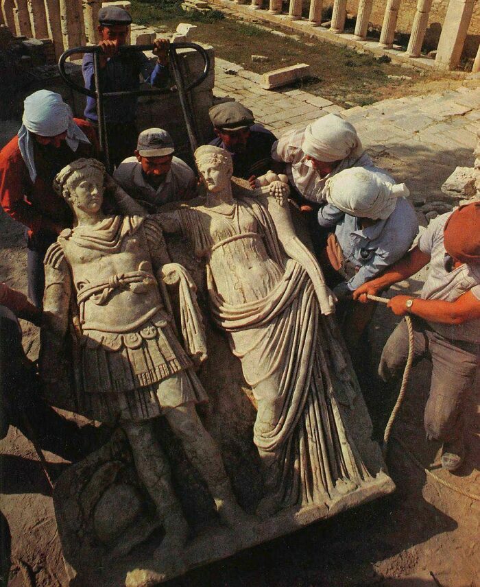 Workers excavating ancient historical statues in archaeological site