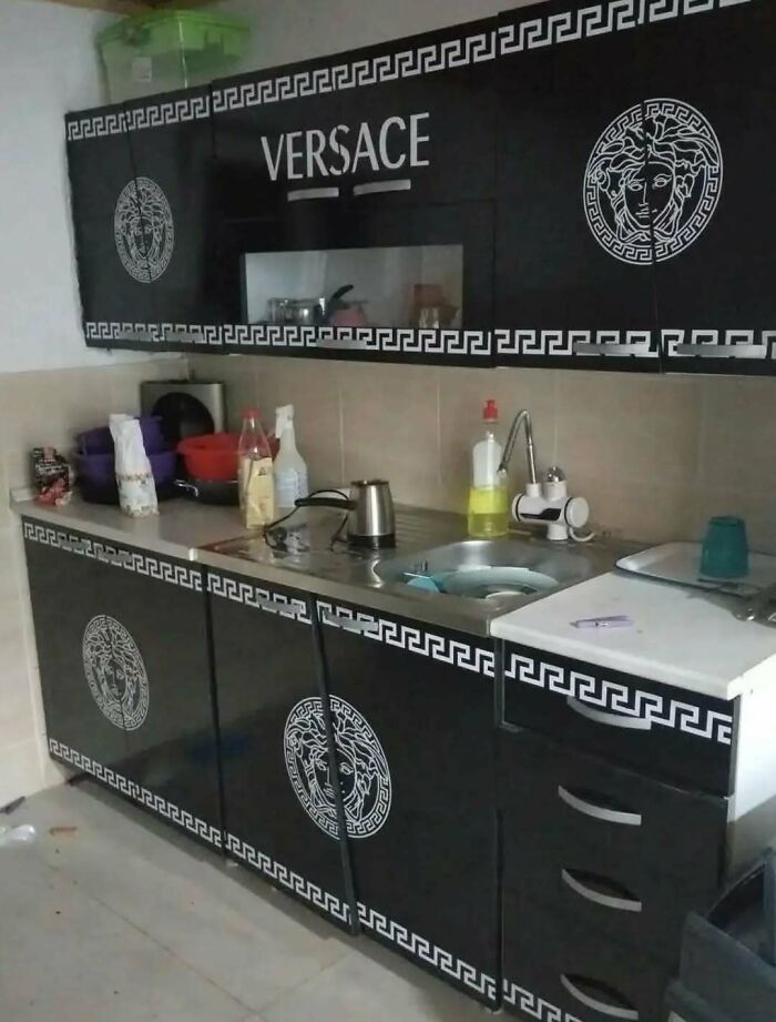 Cursed kitchen with Versace-themed black cabinets and white logos