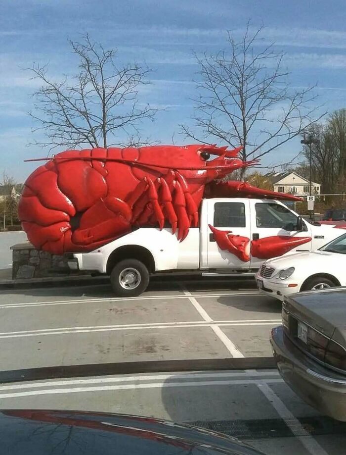 Pickup truck customized with a giant red lobster sculpture in a parking lot