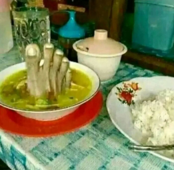 Bowl of soup with realistic severed fingers served with rice on table