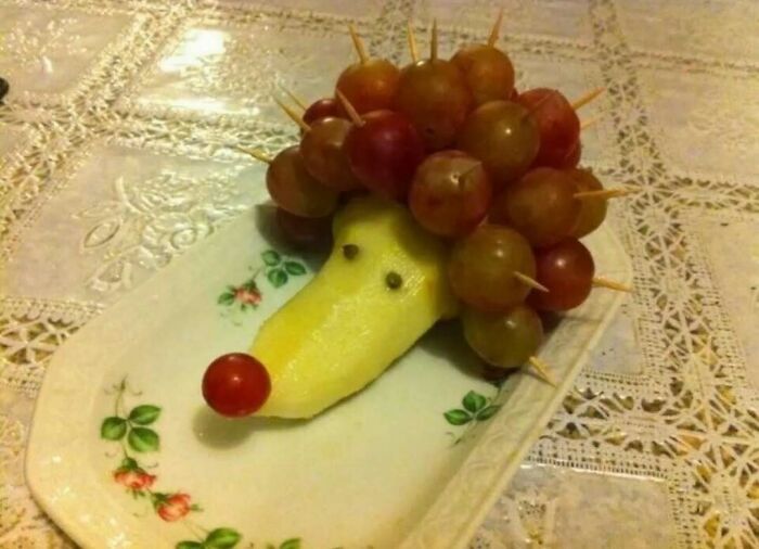 Cursed food art of a hedgehog made from grapes and a pear
