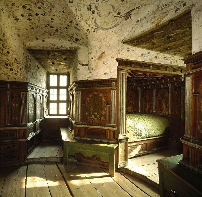 Sunlit vintage historical bedroom with wooden furniture and floral wall paintings