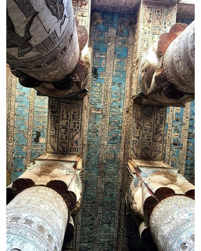 Ancient Egyptian temple ceiling and columns with detailed hieroglyphics and blue sky background