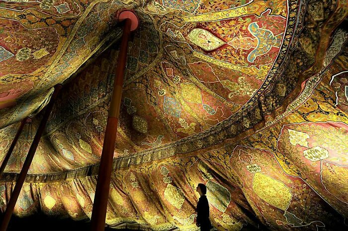 Person admiring large ornate tent ceiling with intricate patterns historical treasure
