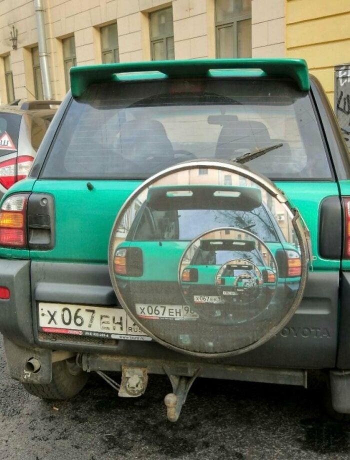 Green SUV with spare tire mirror creating endless reflection effect