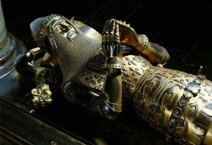 Medieval knight tomb effigy in golden armor with detailed chainmail and gauntlets