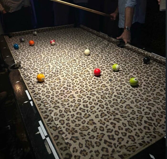 Leopard print billiards table with balls scattered and player aiming cursed images