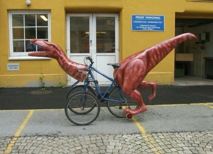 Blue bicycle attached to a realistic dinosaur costume on a city street