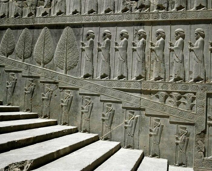 Ancient stone relief with figures and trees along staircase historic treasures