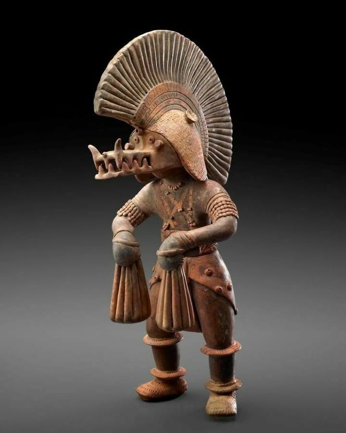 Ancient terracotta warrior figurine with intricate headdress and detailed costume