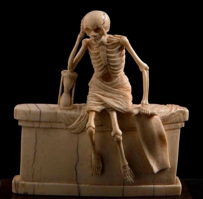 Carved ancient skeleton sculpture holding hourglass historical treasure