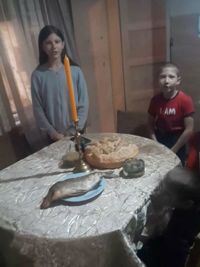 Children with candle and unusual fish and bread setup in cursed images