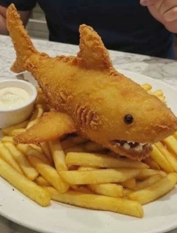 Fried food shaped like a shark served with fries as a cursed image