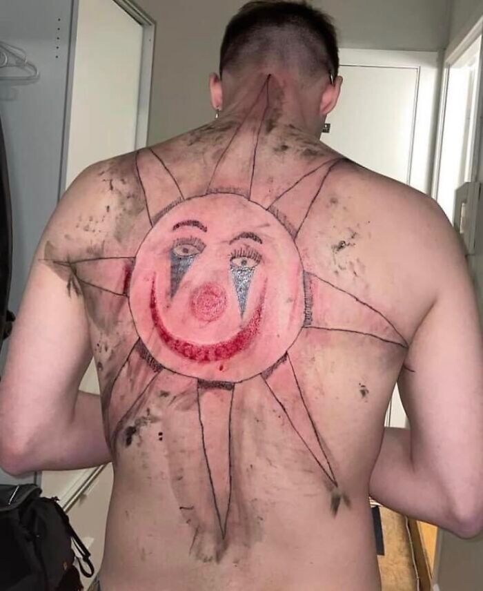 Man with a large sun-shaped clown face tattoo covering his back