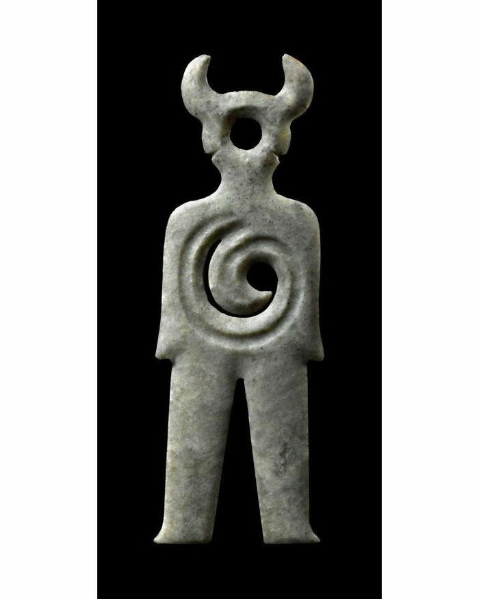 Stone artifact of ancient historical figure with spiral design and horns