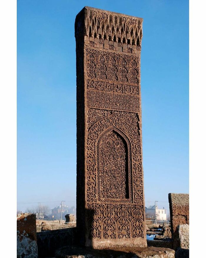 Tall, intricately carved historic standing stone monument under clear blue sky