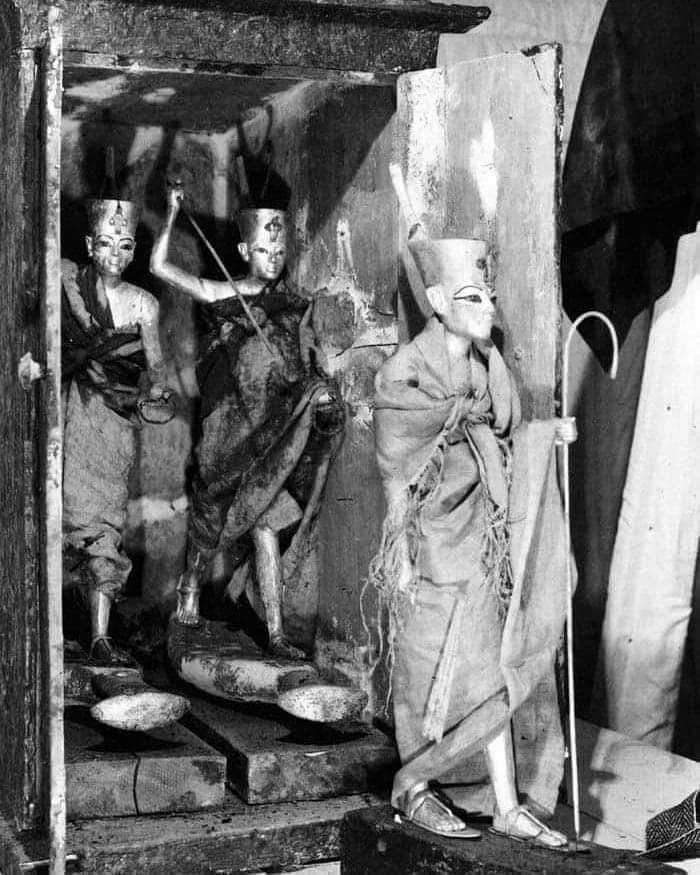 Black and white photo of Egyptian wooden statues inside a tomb historical treasures