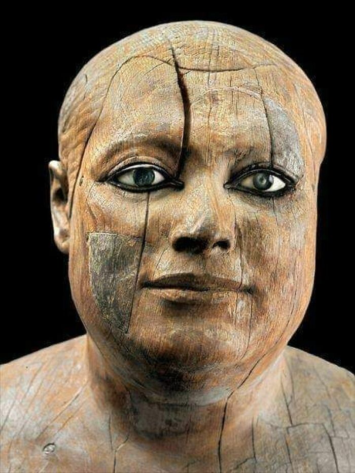 Close-up of an ancient wooden bust with detailed carved facial features and realistic eyes