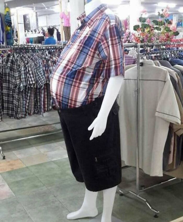 Mannequin with exaggerated belly wearing plaid shirt and black shorts in clothing store