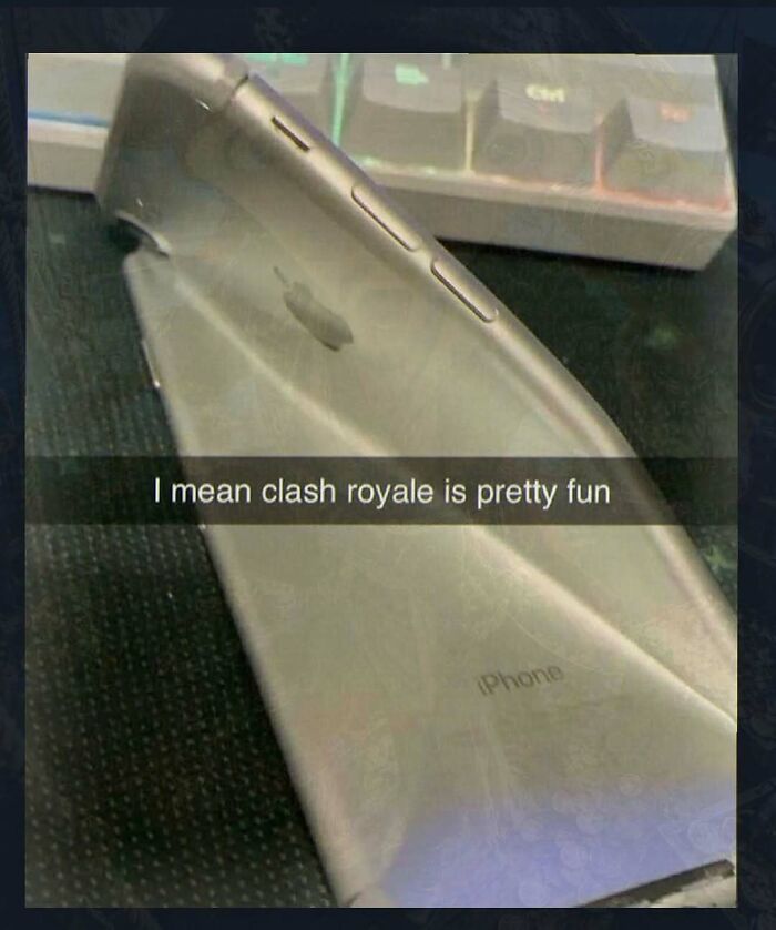An unhinged pic of a severely bent iPhone on a keyboard, with text saying Clash Royale is fun.